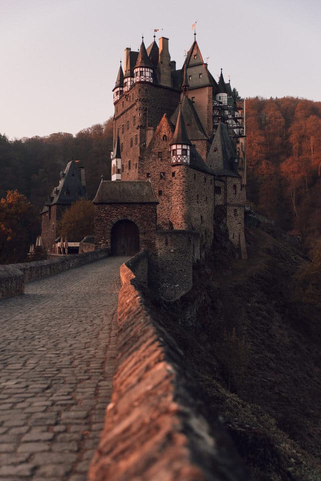 Eltz Castle at sunrise surrounded by autumn foliage