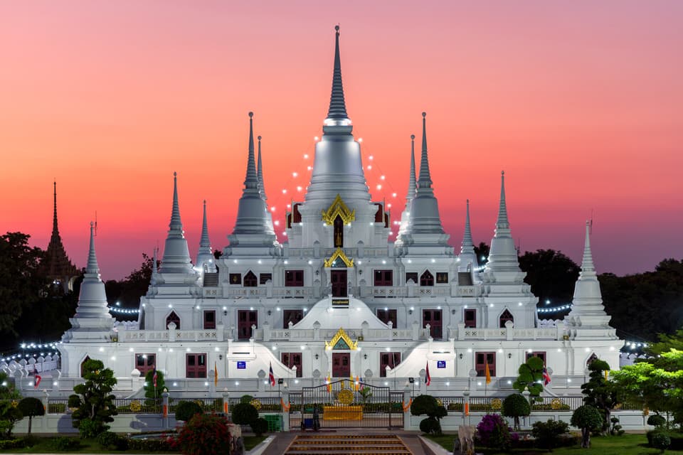 Wat Asokaram temple at sunset with white pagodas and pink sky