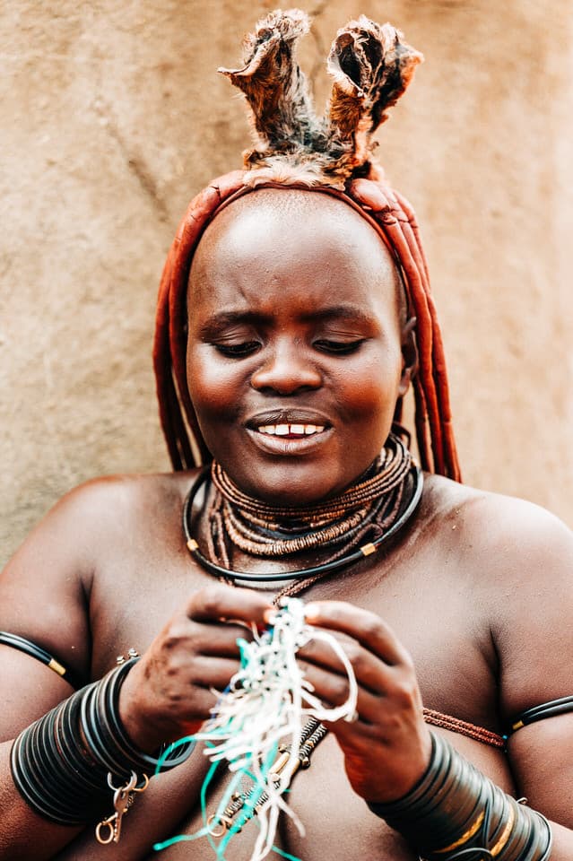 Himba woman weaving jewelry in Namibia