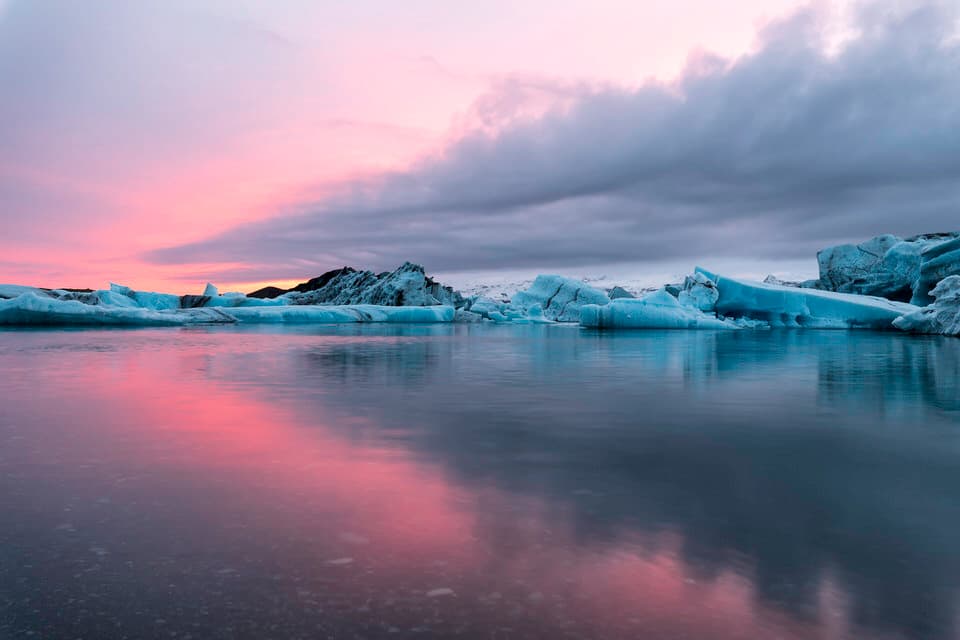 Sunset over the Glacier Lagoon in Iceland with icebergs and colorful sky reflections