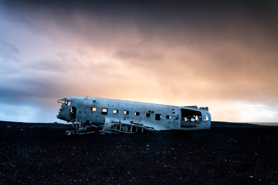 Abandoned DC-3 plane wreck on black sand in Iceland at sunrise