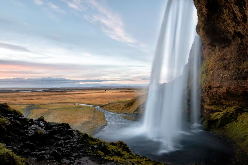 Seljalandsfoss waterfall in Iceland cascading with open plains in the background at sunrise