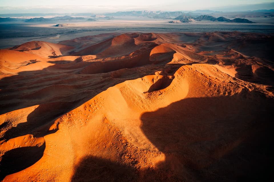 Aerial sunrise view of sand dunes in Sossusvlei, Namibia with golden light and shadows