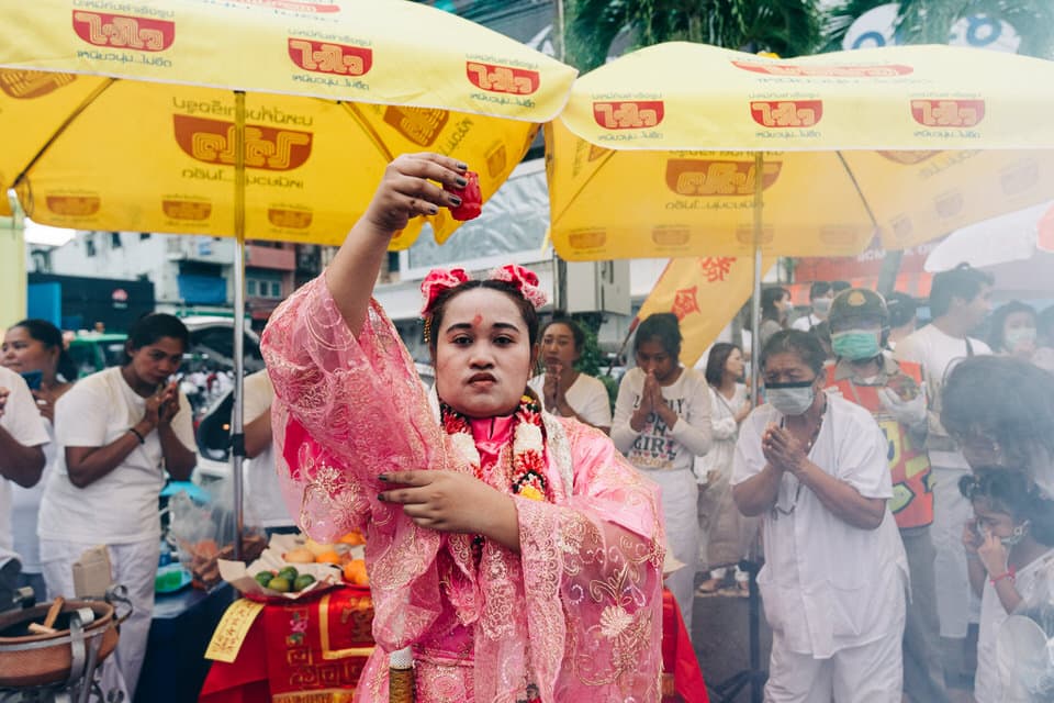 Devotee in pink traditional attire holding a drink at Phuket Vegetarian Festival.