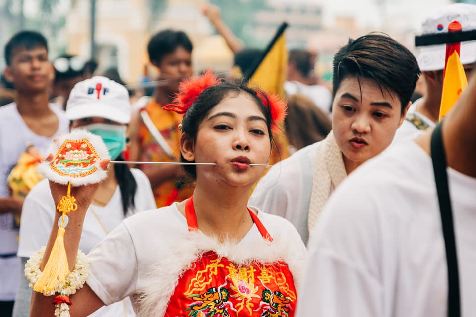 Devotee in traditional attire with a cheek piercing at Phuket Vegetarian Festival.