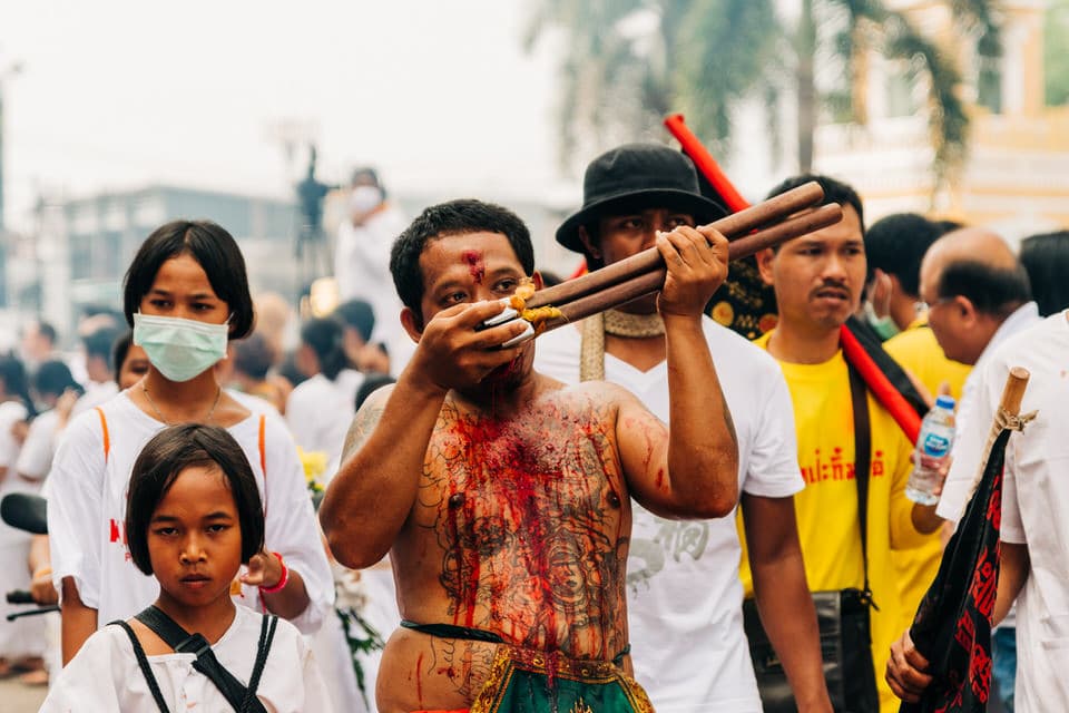 Devotee cutting his tongue with an axe at the Phuket Vegetarian Festival procession.