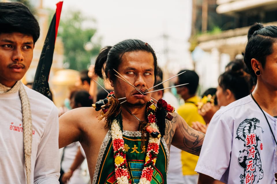 Devotee with cheek piercings during Phuket Vegetarian Festival parade in Thailand.