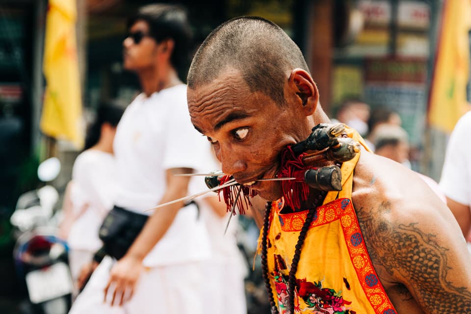 Devotee with cheek piercings at the Phuket Vegetarian Festival parade.